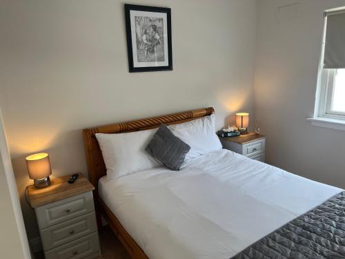 um quarto com uma cama com lençóis brancos e 2 candeeiros em Loughrea Lodge Kilrush County Clare V15 NX53 em Kilrush