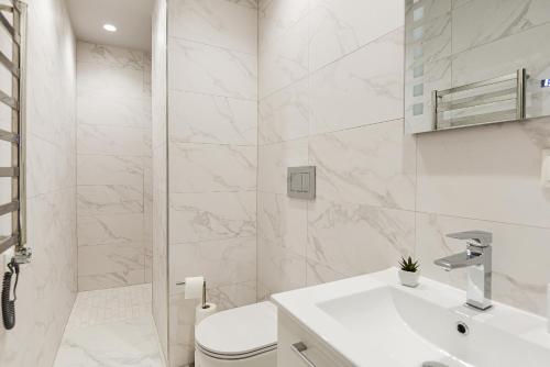 a white bathroom with a toilet and a sink at Apartamentai centre pas Lina in Nida