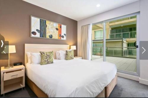 a bedroom with a large bed and a large window at Pier 108 Glenelg in Glenelg