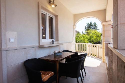 a table and chairs on a porch with a window at Apartments Teskera in Bol