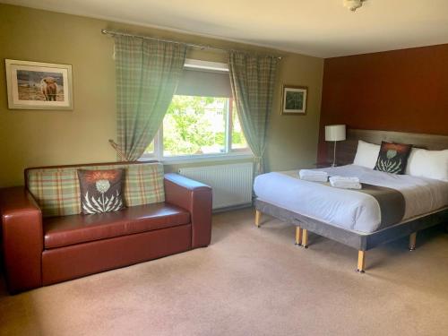 a bedroom with a bed and a chair and a window at Newburgh Inn in Ellon