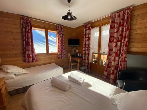 a bedroom with two beds and a desk and a television at Le Schuss in Châtel
