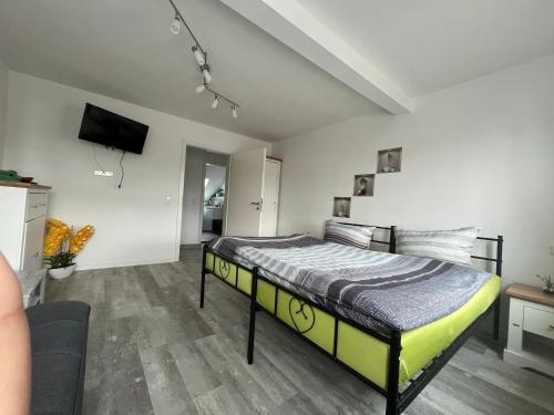 - une chambre avec un lit et une télévision murale dans l'établissement Pension Eckert, à Zwenkau