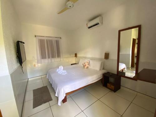 a bedroom with a white bed and a mirror at Pousada Cabana in Jericoacoara