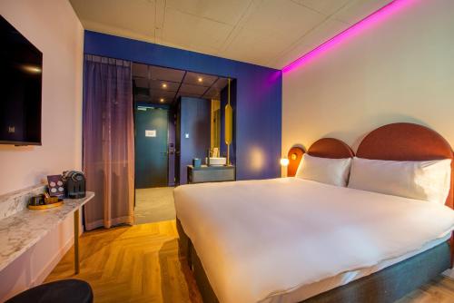 1 dormitorio con 1 cama blanca grande con iluminación púrpura en Hotel VIC en Leiden
