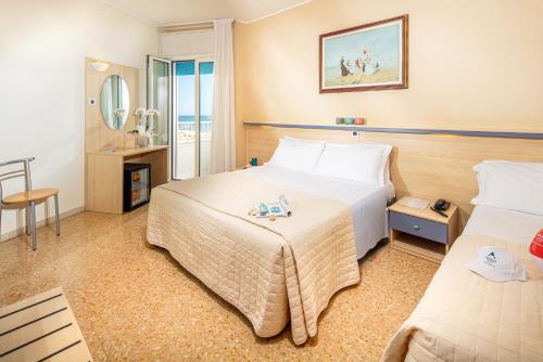 una camera d'albergo con due letti e uno specchio di Hotel Condor a Lido di Jesolo