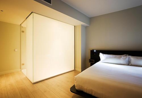 a bedroom with a large white bed and a sliding door at B&B HOTEL Madrid Centro Puerta del Sol in Madrid