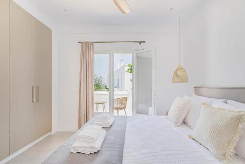 een witte slaapkamer met een bed met handdoeken erop bij Pearl House - Luxurious new beach villa in Spetses stunning view in Spetses
