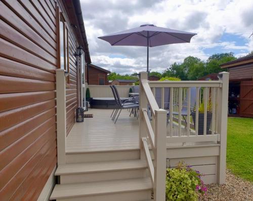 a wooden staircase with an umbrella on a house at Green Acres Retreat Lodge with Hot Tub in Malton
