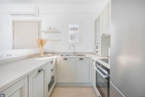 a white kitchen with a sink and a refrigerator at Pearl House - Luxurious new beach villa in Spetses stunning view in Spetses