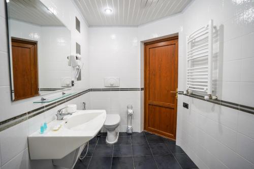 a white bathroom with a sink and a toilet at Natali Hotel in Borjomi