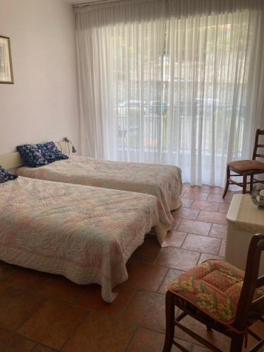 sypialnia z 2 łóżkami, krzesłem i oknem w obiekcie Appartement Front de Mer w Mentonie