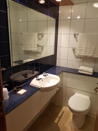 a bathroom with a sink and a toilet and a mirror at V Lodge Manchester in Manchester