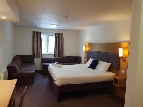 Habitación de hotel con cama y sofá en V Lodge Manchester en Mánchester