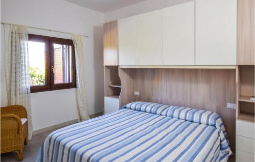 um quarto com uma cama com um cobertor listrado azul e branco em Cozy Home In Budoni With Kitchenette em Budoni