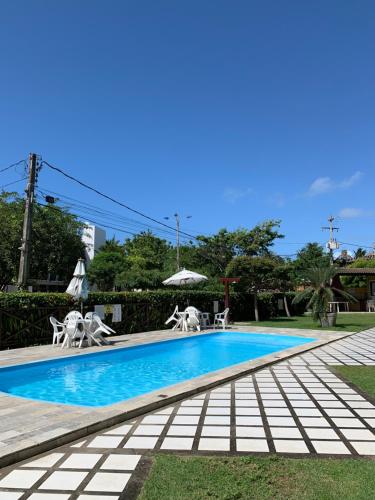 a swimming pool with chairs and an umbrella at Merepe Residence in Porto De Galinhas