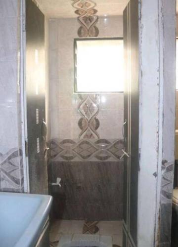 a bathroom with a shower with a toilet and a window at Lexus home in Ahmedabad