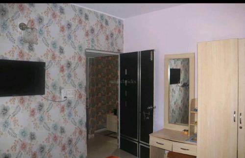 a room with a bathroom with a shower and a television at Lexus home in Ahmedabad
