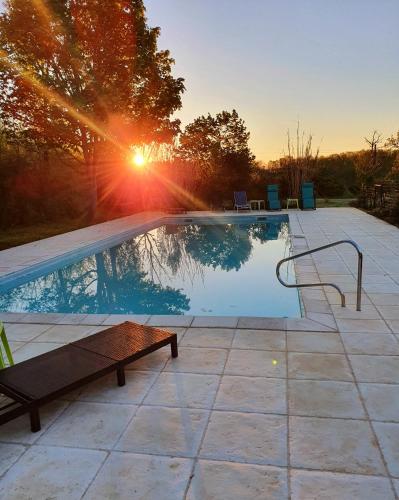 a swimming pool with a bench next to a sunset at Lemoniegites in Lemonie
