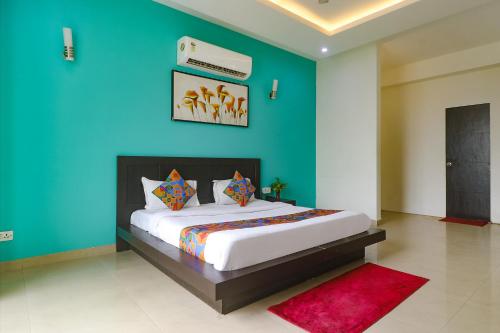 um quarto com uma cama grande e uma parede azul em FabExpress King's One em Noida