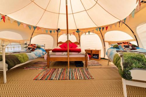 1 dormitorio con 2 camas y sombrilla en Finest Retreats - Beech Lotus Belle Tent en Ilfracombe