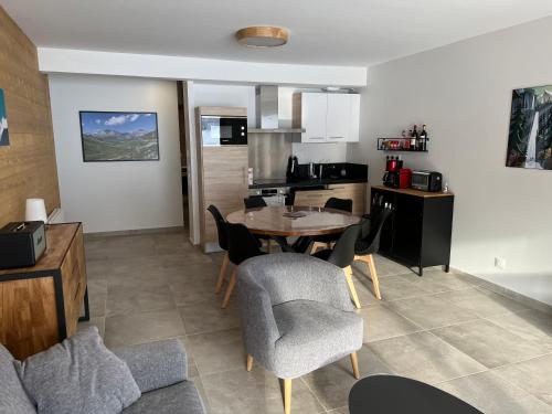 une cuisine et un salon avec une table et des chaises dans l'établissement Oz sur son 31 residence l oree des pistes, à Oz
