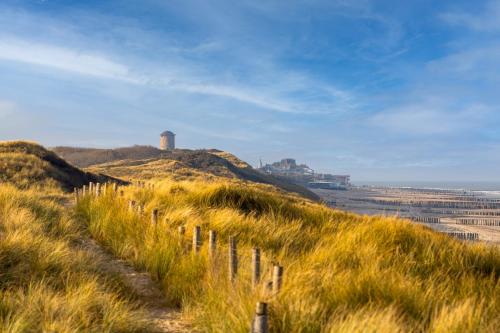 a fence on a hill with a lighthouse on it at Residenties en bungalow Royal Domburg in Domburg
