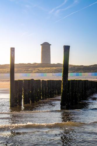 a pier in the water with a lighthouse in the background at Residenties en bungalow Royal Domburg in Domburg