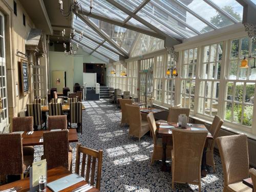 un comedor con mesas, sillas y ventanas en Manor Hotel by Greene King Inns en Yeovil