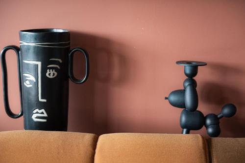 a black cup and a small black figurine on a couch at Tribe Carcassonne in Carcassonne