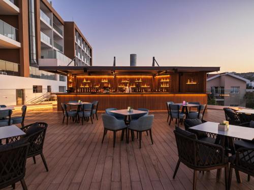 an outdoor patio with tables and chairs and a bar at Leonardo Crystal Cove Hotel & Spa – Adults only in Protaras