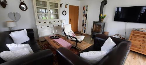 sala de estar con muebles de cuero negro y TV en Alpenglück, en Burgberg