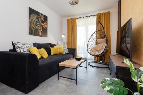 een woonkamer met een zwarte bank en een tafel bij Baltic Marina Residence Apartments by Renters in Kołobrzeg