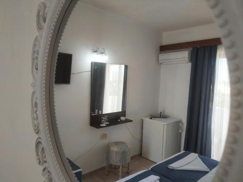 a mirror in a room with a bed and a refrigerator at Hotel Narkissos in Archangelos
