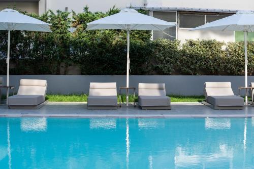 a group of chairs and umbrellas next to a swimming pool at Oktober Downtown Boutique Hotel in Rhodes Town