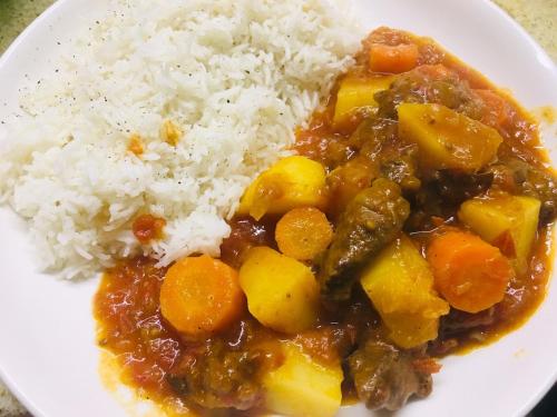 a white plate of food with rice and stew at Pole Pole Beach House in Watamu