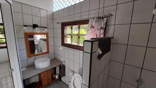 a bathroom with a toilet and a sink and a window at Casa Hibiscus in Ojochal