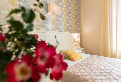 a bedroom with a bed with pink flowers in the foreground at Hotel Corso in Orvieto