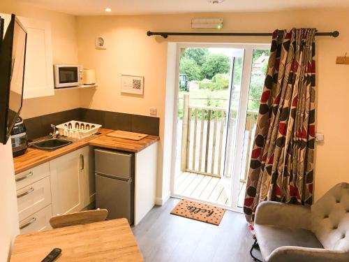 Blakeney的住宿－Deers Leap, A modern new personal double bedroom holiday let in The Forest Of Dean，厨房设有通往庭院的门。