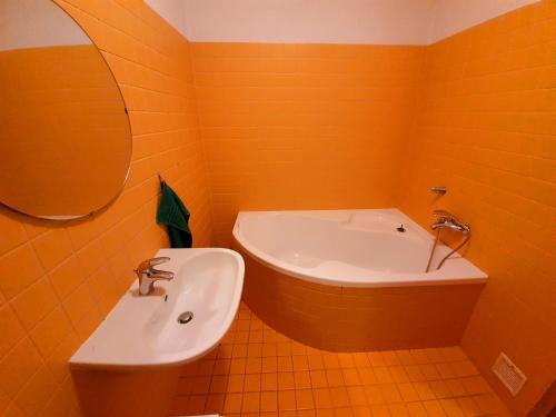 an orange bathroom with a sink and a tub at Apartmán U Slunečnice in Husinec