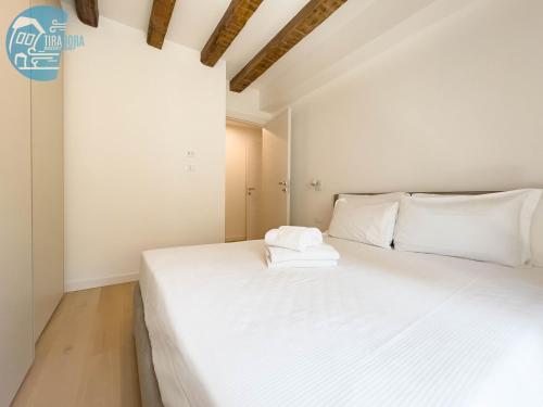 białe łóżko w pokoju z białymi ścianami w obiekcie Cavana 10 Tirabora Short Rent w Trieście