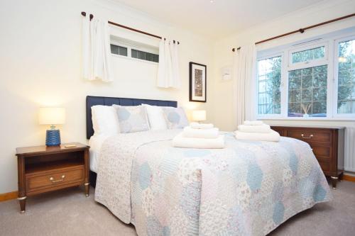 a bedroom with a large bed with two lamps on it at Little Crossways , Goodwood in Chichester