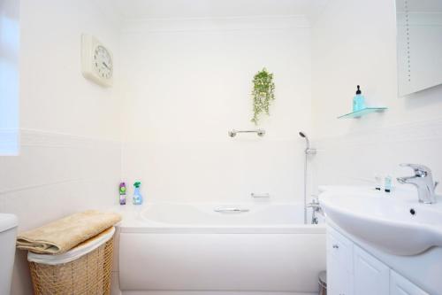 a white bathroom with a tub and a sink at Little Crossways , Goodwood in Chichester