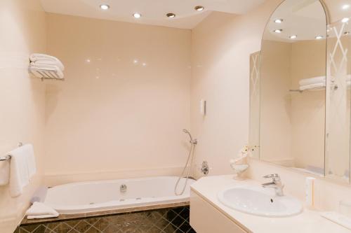 a white bathroom with a tub and a sink at Elias Beach Hotel in Limassol