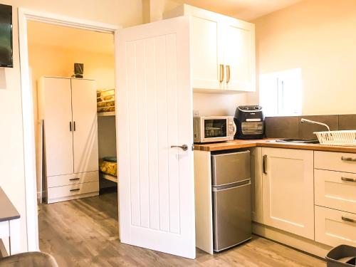 a kitchen with white cabinets and a white door at Rabbits Warren, 2 Single Bed Holiday Let in The Forest of Dean in Blakeney