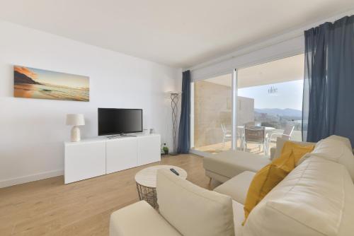 a living room with a white couch and a tv at Apartamento de lujo vista mar en Torrox Costa in Torrox Costa