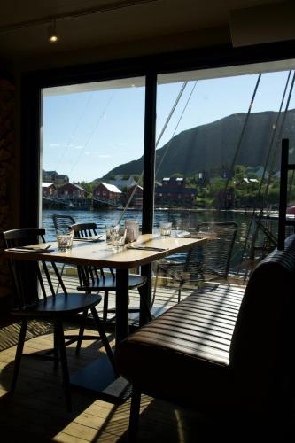 a table and chairs on a balcony with a view of the water at Solsiden Brygge Rorbuer in Ballstad