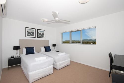 a white bedroom with a bed and a couch at Allure Hotel & Apartments in Townsville
