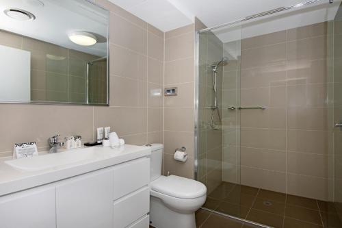 a bathroom with a toilet sink and a shower at Allure Hotel & Apartments in Townsville