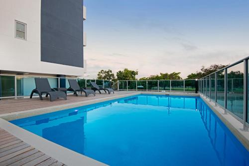 a swimming pool with two chairs next to a building at Allure Hotel & Apartments in Townsville